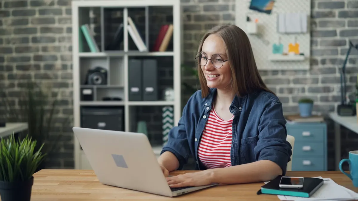 A woman at a laptop recording a short video message from her desk